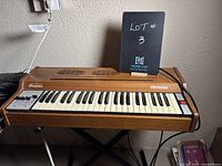 Front angled view of Orcana 600 Supreme portable electric organ with keyboard and control switches visible, showing the brown finish and speaker grills on top.