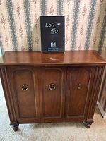 Front view of the wooden sideboard showing three cupboard doors with metal ring handles and keyhole on the right door.