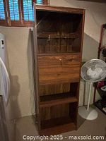 Full view of the wooden shelving unit showing glass doors on top, drop-down cupboard in the middle, and bottom open shelf.