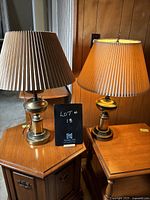 Two vintage brass table lamps on small wooden tables, beige and light brown pleated shades, brass bases, 32 inches tall.