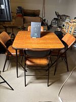 Square vintage brown vinyl card table with metal legs surrounded by 4 matching folding chairs with brown vinyl seats and backs.