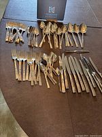 Full layout of the flatware set including forks, spoons, knives arranged on a table.