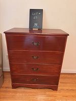 Front view of vintage wooden dresser showing four drawers with brass handles.
