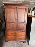 Front view of vintage wooden Thomasville wardrobe armoire with two upper doors and four lower drawers.