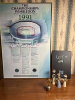 Front image showing 1991 Wimbledon Championships poster with tennis figurines and metallic trinket beside it.