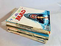 Stack of 23 vintage MAD magazines, close-up side view showing magazine thickness and edge wear