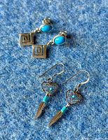 Two pairs of sterling silver and turquoise earrings on blue fabric background, showing pairing and details