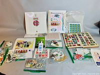 Overview of the mixed lot showing multiple album pages, loose stamps in bags, block sheets, and various stamp collection items