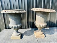Front view of both urn planters side by side against metal backdrop