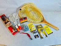 Photo showing the full assortment of fishing accessories including landing nets, packaging with hooks and lures, bobbers, and stringer chain.