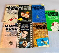 Seven Pan Books paperback James Bond novels arranged side by side on a surface, showing front covers.