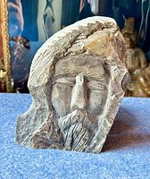 Front view showing bearded man's face, head covering details, and artist signature in lower corner.