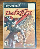 Front cover of Devil Kings PlayStation 2 game case with original artwork featuring armored warrior and characters.