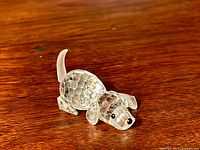 Swarovski crystal beagle figurine sitting on a wood surface, showing clear faceted crystal body and frosted tail.