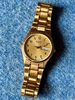 Front view of the Bulova watch showing gold-tone dial, Arabic numerals, and day-date window.