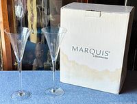 Pair of clear crystal champagne flutes with original Marquis by Waterford box visible in background.