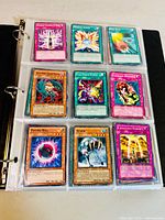 Photo showing 9 Yu-Gi-Oh! trading cards in protective sleeves inside binder, including 'Cosmic Vacuum G Harl R', 'Fenrir', and 'Collected Power' cards.