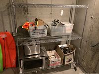First baker's rack with various stored items including a toaster oven, plastic bin, and boxes.