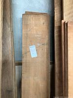 Four rough-sawn black walnut wood planks stacked upright, one with a small white label attached.