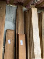 Stack of black walnut wood planks leaning against wall under insulation