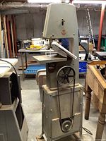 Full view of band saw on stand showing frame, table, handwheel and belt drive