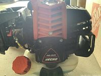 Close-up photo showing Echo PAS-2620 trimmer engine with orange cap and black engine housing.