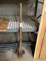 Full view of the 62-inch wooden J-hook resting on a metal shelving unit, showing length and overall condition.