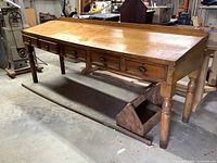 Full view of vintage oak planers table showing 5 drawers on the front, turned legs, and raised backsplash along sides and back.