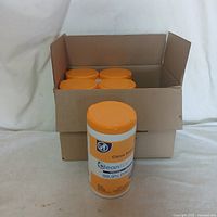 Box with 5 canisters of disinfectant wipes, 4 canisters in the box and 1 canister out in front.