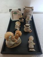 All 8 ceramic figurines and 2 picture frames displayed on a tray, showing girls and kids with pastel colors and hats