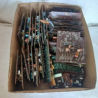 Box filled with multiple computer circuit boards arranged upright, showing a variety of components and connectors on brown PCBs.