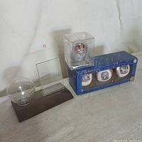 Photo showing the empty wooden display holder with acrylic holders next to the boxed set of three Diamondbacks baseballs in original packaging and the Schilling baseball in its clear plastic display case.