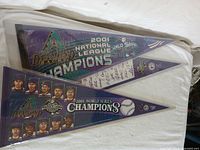 View showing two pennants laid flat, including National League Champions and World Series Champions versions with player images and signatures