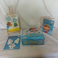 Photo of all lot items - three books displayed and Dr. Seuss Trivia Game tin box