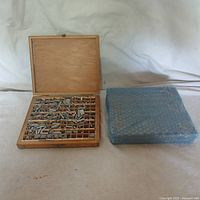 Photo of one open wooden case with dye stamps and one wrapped wooden case