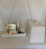 Full view of Elna Lock F4 sewing machine in white carrying case with lid removed, showing the machine and accessories inside the base tray.
