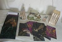 Wide view of the lot showing the books, figurines, postcards, and decorative box on a white surface.