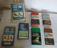 Photo of 7 hardcover outdoor field guides including 4 Audubon guides and 3 Peterson guides laid out on a surface.