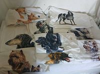 Lot of 10 white XL t-shirts laid out showing different dog face prints, realistic and detailed.