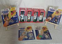 Full lot view showing four Starting Lineup baseball figure sets with players, posters, and cards in original packaging standing upright, along with four collectible series baseball bobbleheads in sealed boxes arranged behind them.