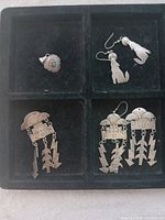 Four sterling silver jewelry pieces displayed on black tray: two pairs of earrings and one brooch with Indigenous American design.