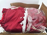 Box containing artificial flowers wrapped in plastic and red fabric.