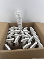 Box containing 25 sealed disinfectant spray bottles arranged inside with white trigger tops visible