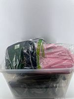 Two insulated lunch bags, black and pink, sealed in plastic and stored in a tray
