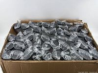 Box filled with multiple transparent plastic cups with black lids, all individually sealed in clear plastic.