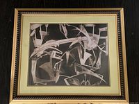 Front view of the framed abstract artwork showing geometric shapes and lines in white and gray on black background.