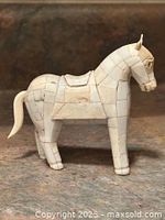 Front profile view of the antique carved bone horse figurine showing detailed segmented bone construction and saddle.