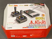 Box showing Atari branding and 200+ preloaded games, includes two joysticks, console, and logos of classic games.