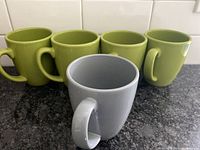 Front view showing four olive green Corelle mugs and one gray Corelle mug with smooth finish and handles.