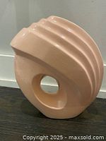 Front view of a large peach-colored ceramic Art Deco vase with hollow circular center and ridged top design